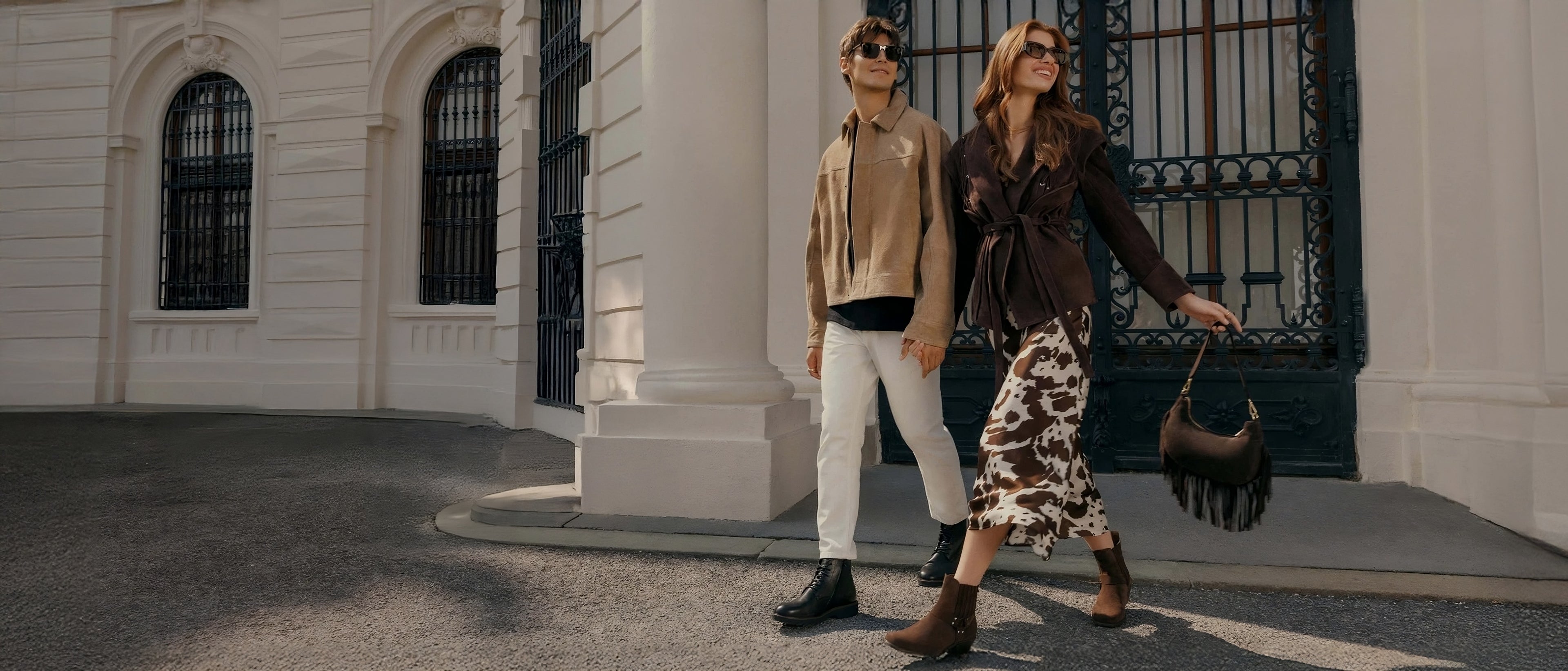 Two people walking together in front of a building with architectural details.